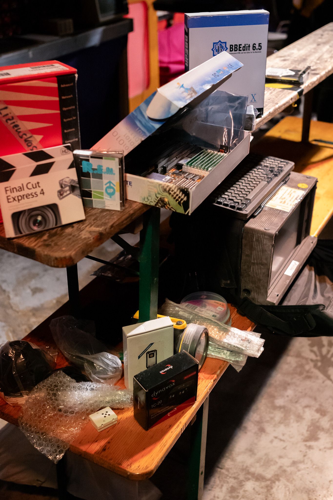Assorted electronics and software CDs on a table, a rugged vintage computer sits on the table as well